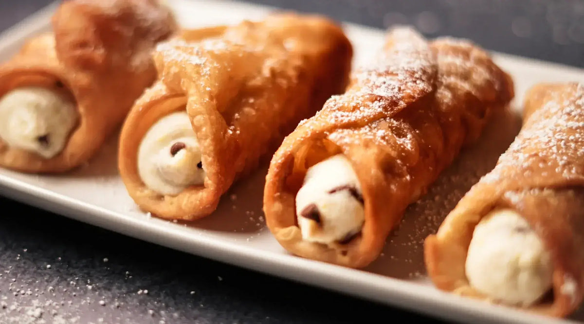 Cannoli italiens authentiques garnis de ricotta et pépites de chocolat, disposés sur une assiette blanche, saupoudrés de sucre glace.