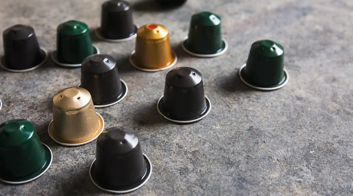 Capsules Nespresso de différentes couleurs disposées sur un plan de travail, illustrant le concept de café réutilisable et durable.