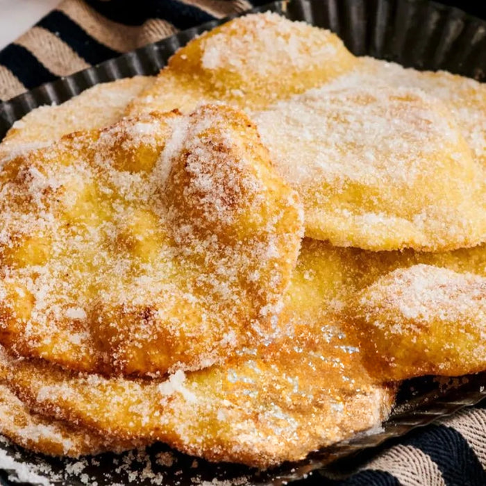 Cresciole dorées et saupoudrées de sucre, servies sur une assiette