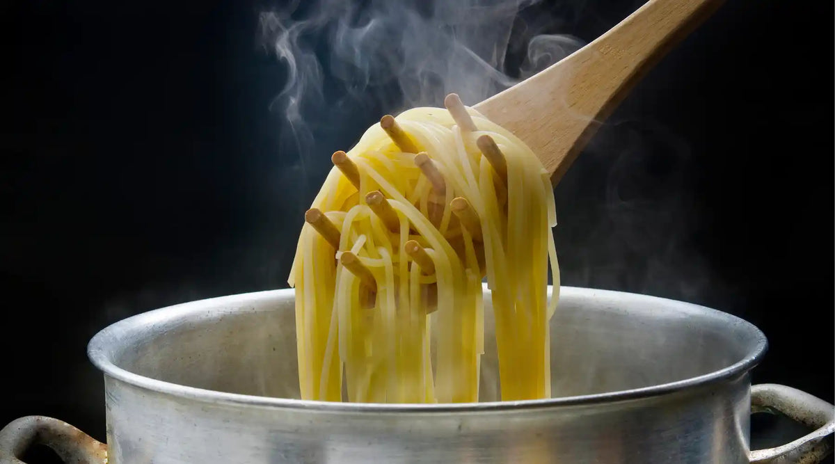Cuisson des pâtes dans une casserole avec des spaghetti soulevés à la cuillère en bois