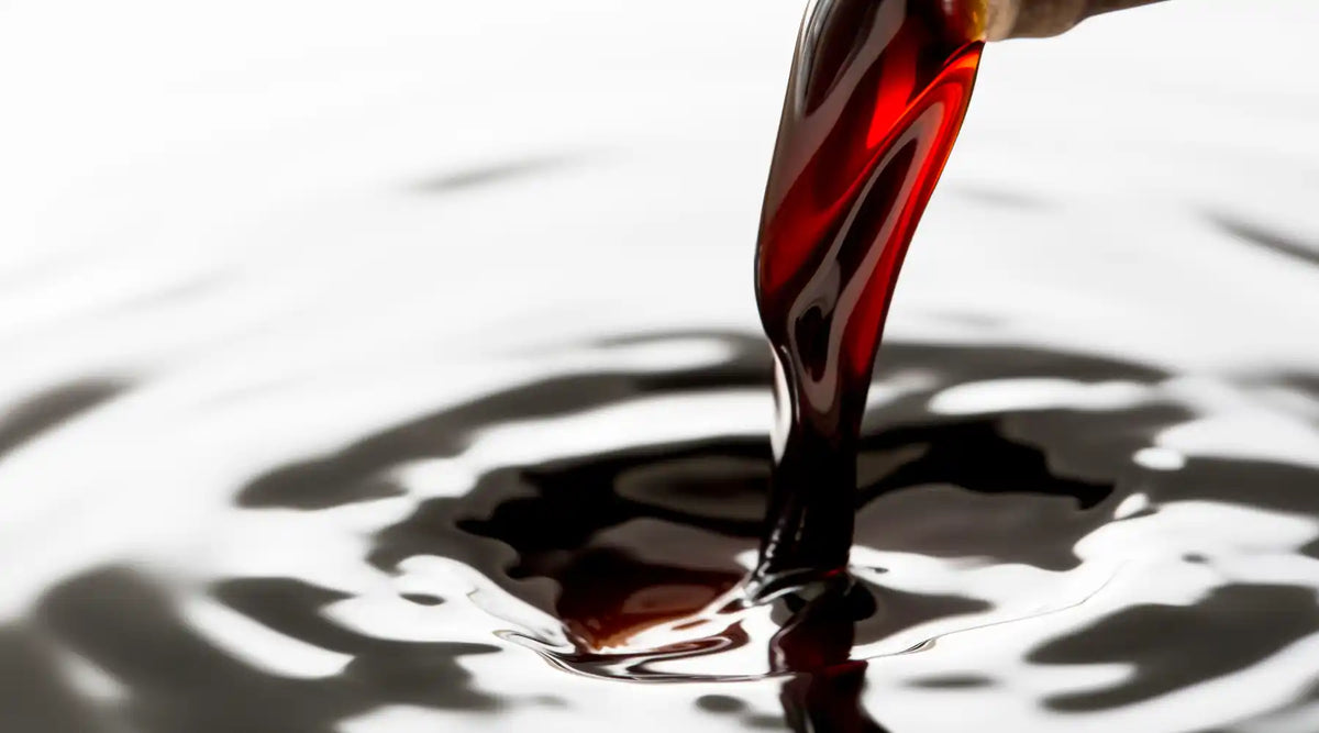 Vinaigre balsamique sombre et brillant versé dans un liquide, texture onctueuse et reflet gourmet