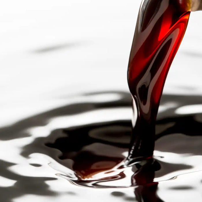 Vinaigre balsamique sombre et brillant versé dans un liquide, texture onctueuse et reflet gourmet