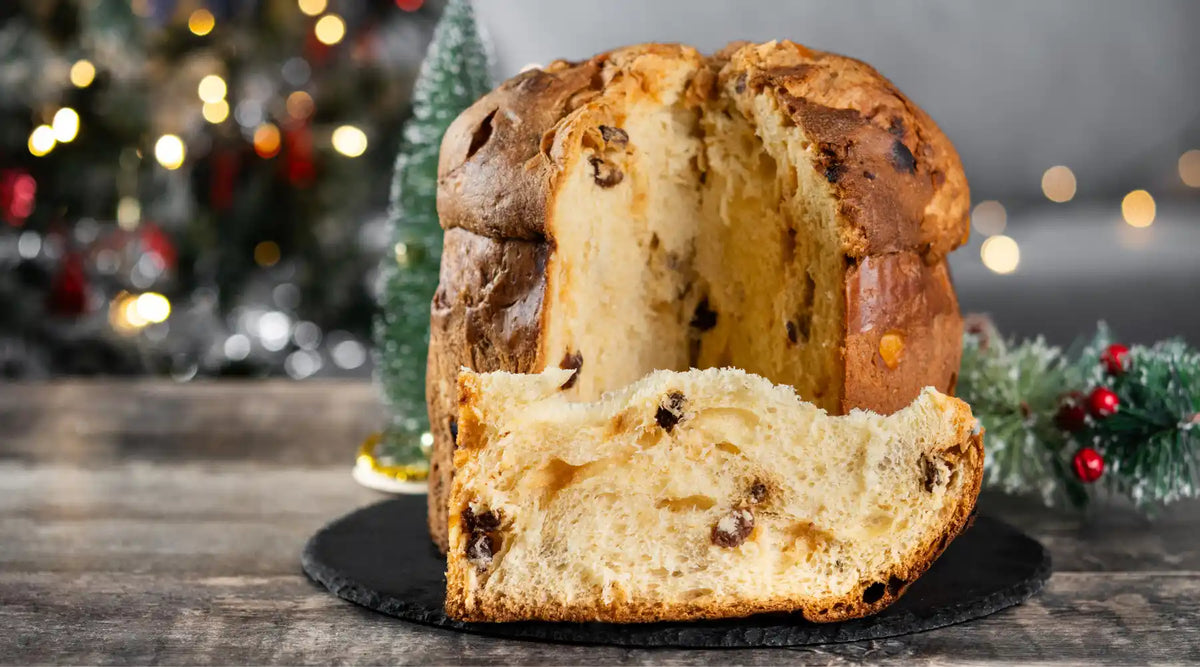 Panettone traditionnel posé sur une table en bois, coupé pour révéler sa texture moelleuse.