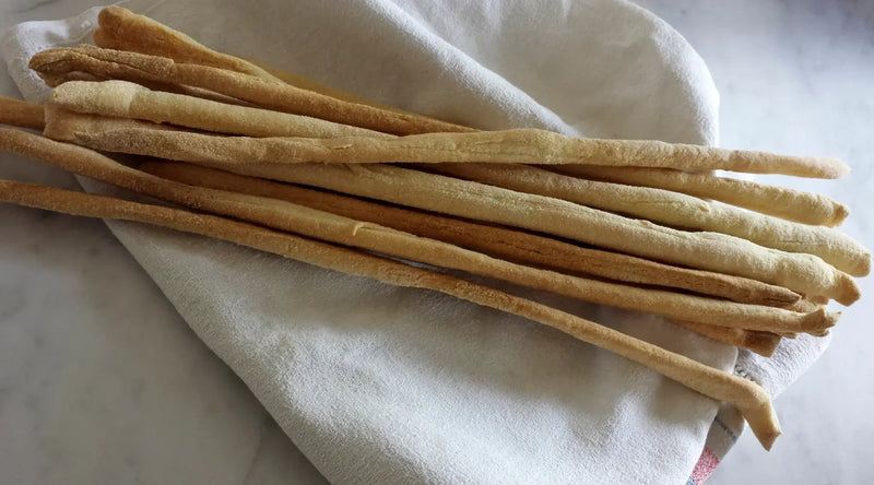 Gressin Nature Il Roero 300g posés sur une nappe blanche, idéals pour les apéritifs et les repas gourmands, produits en Italie.